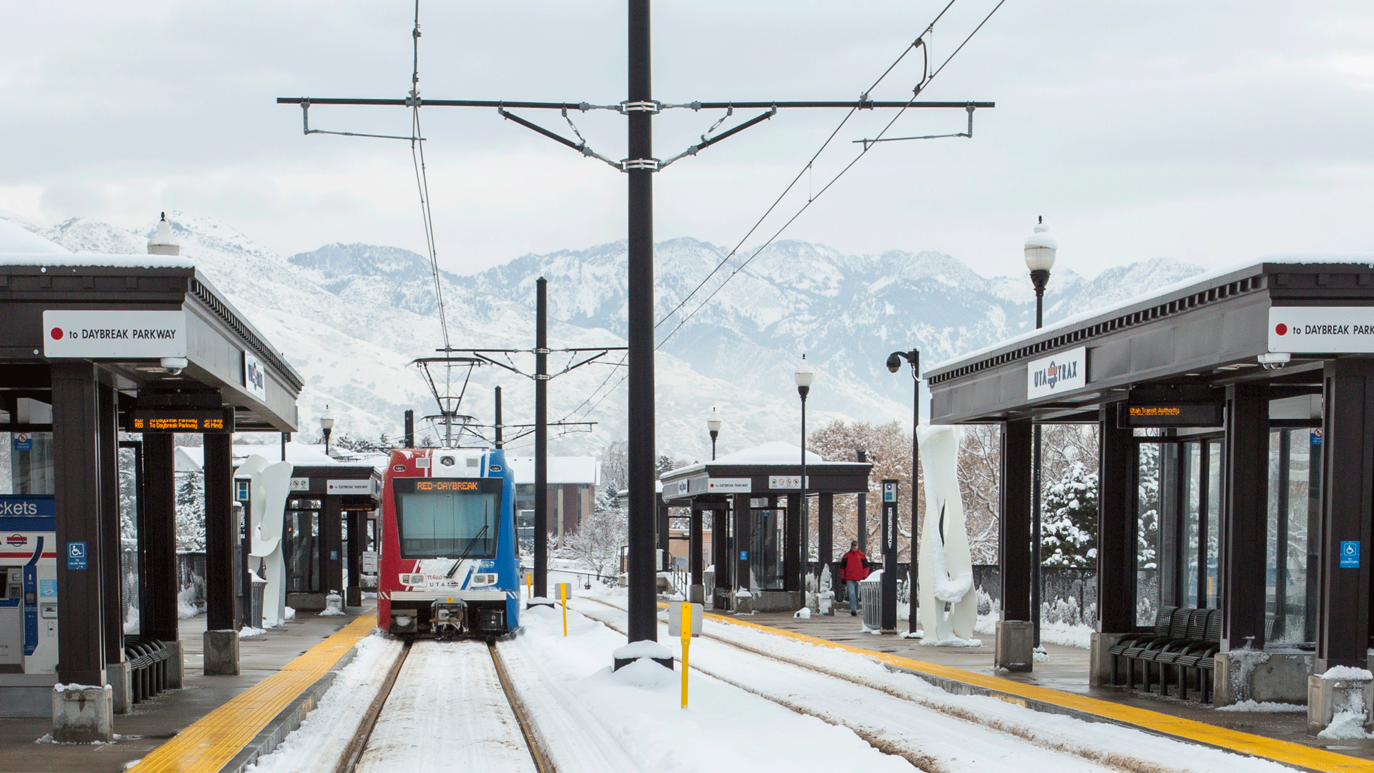 An eastbound light rail train arrives at the Stadium station on a snowy day.