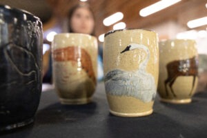 A close-up view of four ceramic mugs painted with different birds.